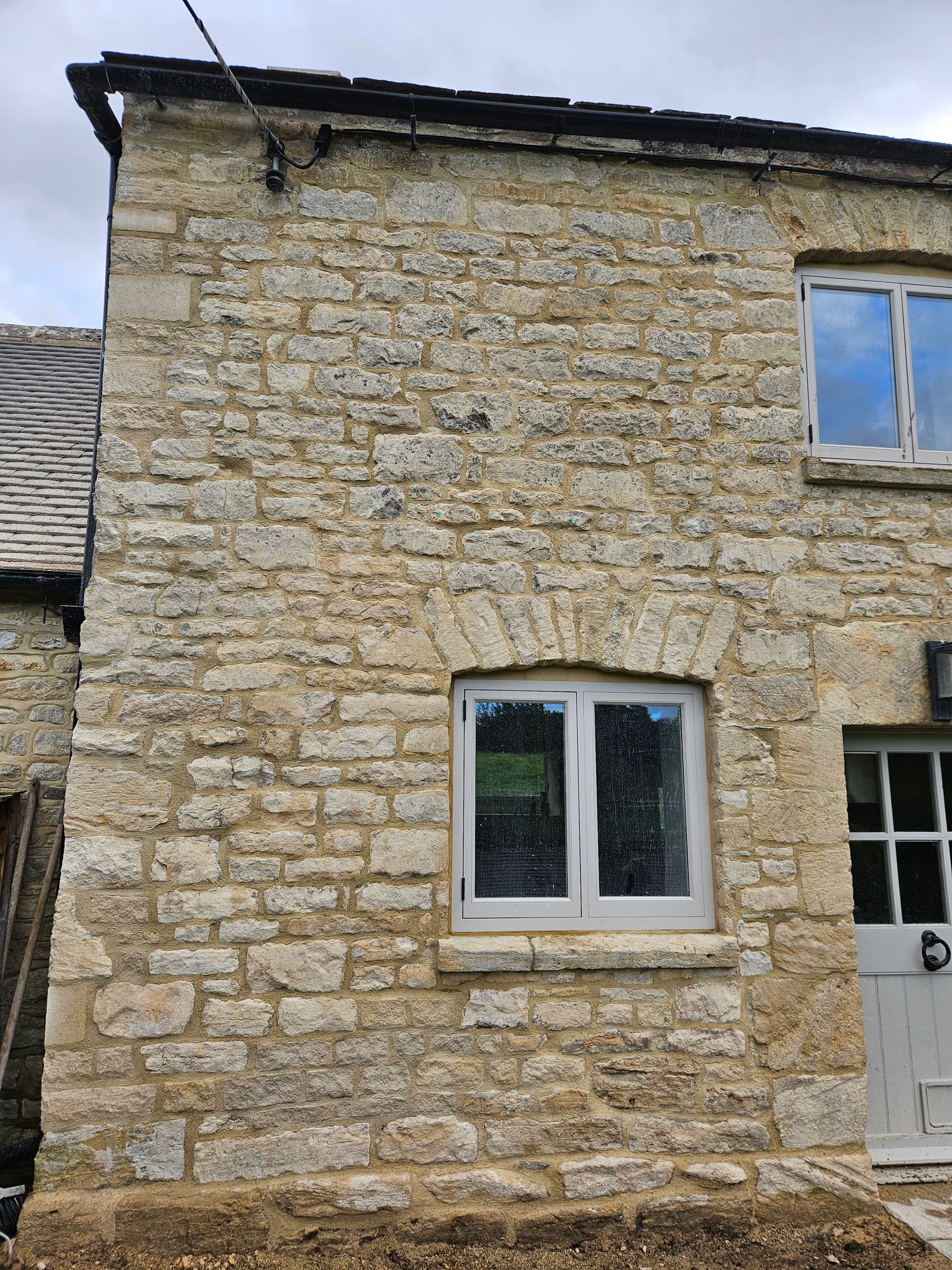 The same end bay after the work, with replaced stones, crisp lime pointing and a clean base course
